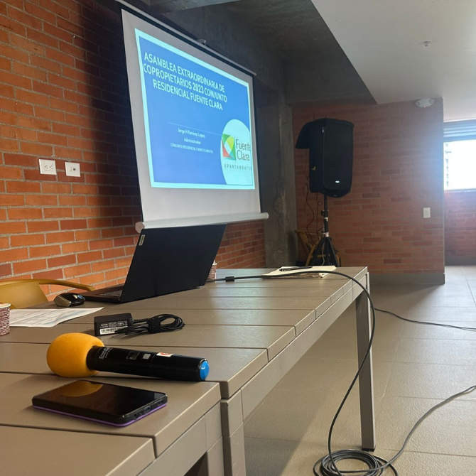 Salón preparado para una Asamblea con proyección de diapositiva, equipo de sonido y micrófono. Logística de Asambleas y Eventos en Colombia