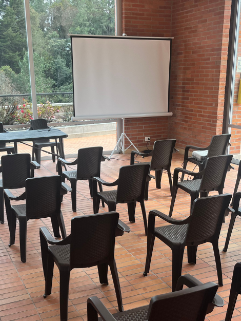 Sala de reuniones al aire libre con sillas negras y una pantalla de proyección blanca, listo para una asamblea o presentación. paquete de servicios asambleas sonido proyección y grabación